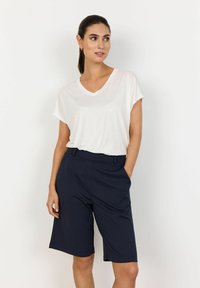 White V-neck t-shirt with short sleeves paired with navy blue knee-length shorts featuring a smooth texture and side pockets.
