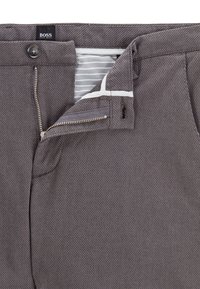 Grå vävda byxor med dragkedja och knappstängning. Har ett randigt innerfoder och en mjuk textur, med subtila sömnadsdetaljer.