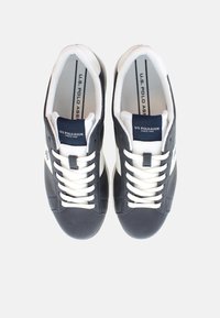 Námořnické modré tenisky s bílými akcenty, kožené a textilní materiály, rovné bílé tkaničky, polstrovaný límec a značkový jazyk.