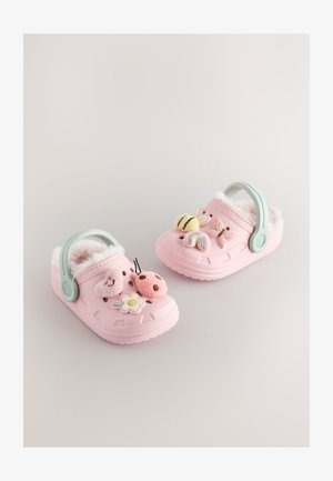 Roze klompe od pjene s mekanim krznenim umetcima, ukrašene dekorativnim zakrpama s motivima bubamare, leptira, cvijeta i duge, uz zeleni remen.