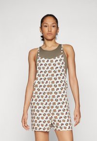Katoenen overall romper met een bloemmotief in oranje, groen en blauw op een witte achtergrond. Kenmerkt zich door een effen olijfgroene top.
