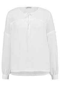 Blusa bianca a maniche lunghe con scollatura rotonda, dettaglio con laccetti sul davanti e tessuto trasparente a pois sulle spalle. Presenta accenti in pizzo.
