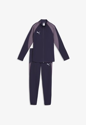 Marineblauw en grijs Puma trainingspak met ritssluiting en elastische boorden aan de broekspijpen, voorzien van het Puma-logo op de borst en dij.