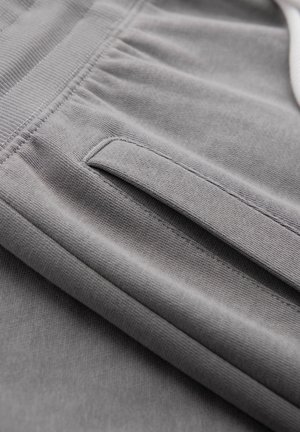 Šedé kalhoty z látky s elastickým pasem a vodorovnou kapsou s látkovou klopou.