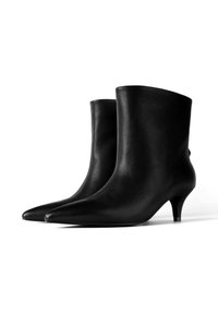 Mustad mustad talvekingad terava ninaga ja kitsaste kontsadega. Sile tekstuur ja voolav disain, mis sisaldab lihtsat, minimalistlikku stiili.