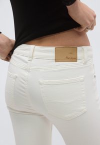 Άσπρο τζιν από denim με εφαρμοστή σχεδίαση, διαθέτοντας δερμάτινο ταμπελάκι σε ταμπά απόχρωση με το λογότυπο "Pepe Jeans London" και σταθερές πίσω τσέπες.