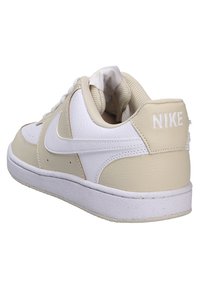 Zapatillas de deporte de cuero beige con acentos blancos, que cuentan con un acabado texturizado, perforaciones para la transpirabilidad y un cuello del tobillo acolchado.