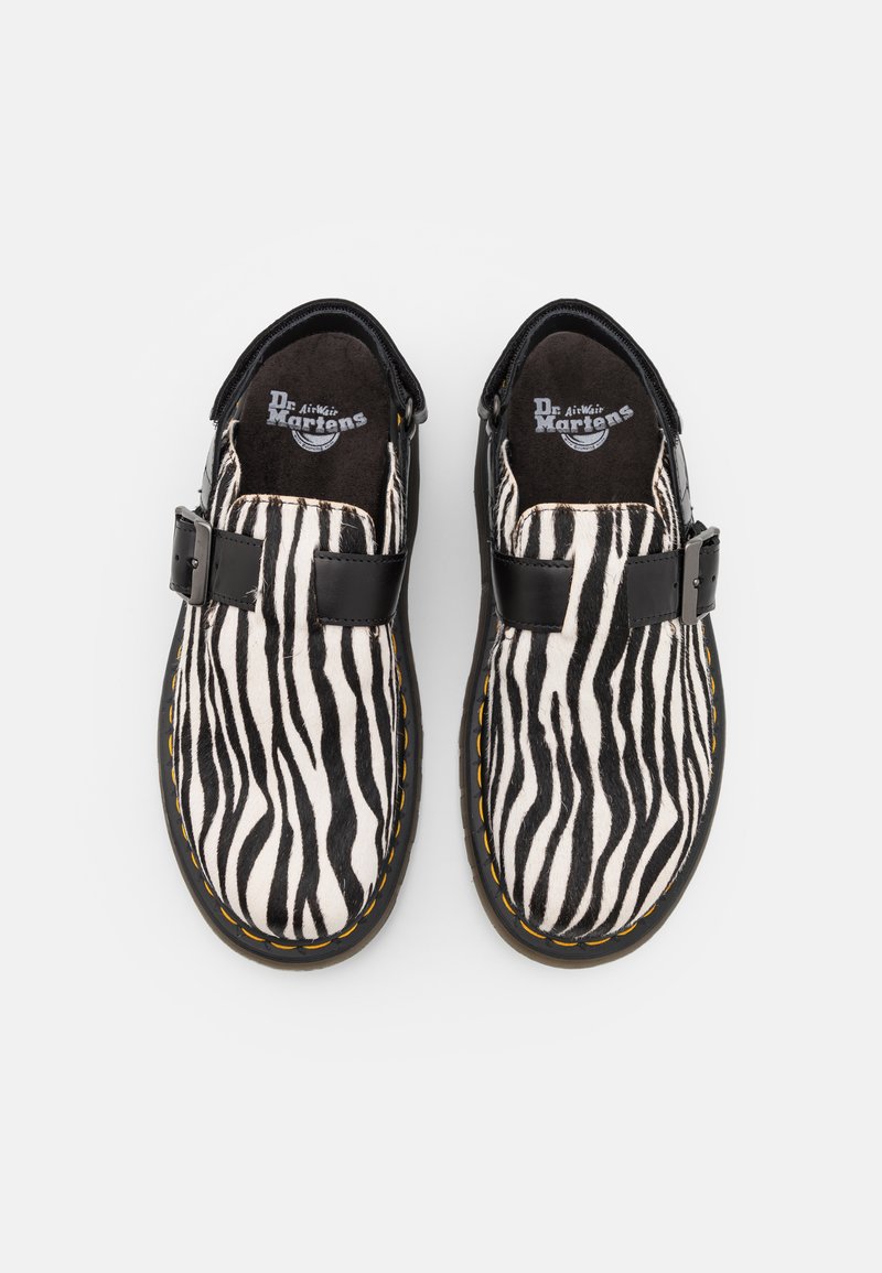 Schwarz-weiße Schuhe mit Zebra-Muster, glatter Textur, einem schwarzen Schnallenriemen und gelben Nähten entlang der Kanten.
