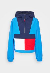 Blue and navy hooded jacket with a half zipper, featuring a front pocket in red, white, and blue color block design. Elastic cuffs.
