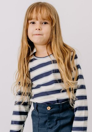 Gestreiftes Langarmhemd in Creme mit Marineblauen Streifen, kombiniert mit Marineblauen Hosen mit Knopfdetails. Glattes Gewebe, lockere Passform.
