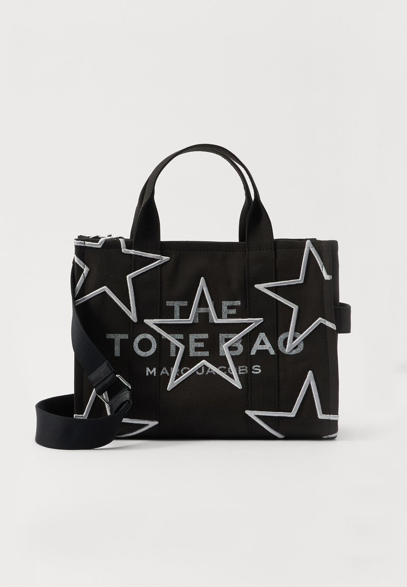 Black Marc Jacobs tote bag with silver outlined stars, two handles, a detachable shoulder strap, and printed brand text on the front.