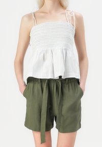 Haut court smocké à rayures blanches et bleu clair avec fines bretelles, associé à un short olive à cordon de serrage avec poches latérales.