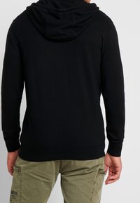 Black hooded sweatshirt with a clean design, ribbed cuffs, and hem. Cotton material, fitted silhouette, and a soft texture.