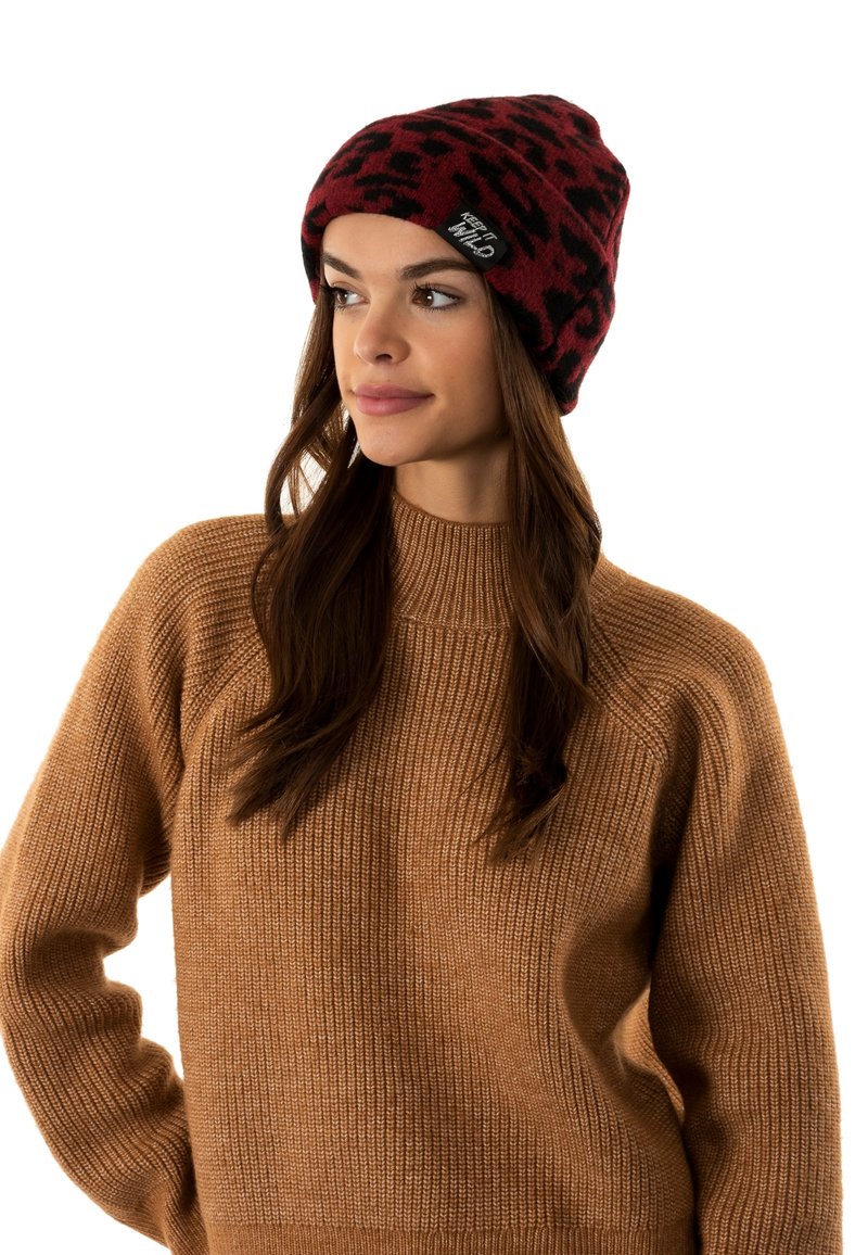 Gorro de leopardo rojo y negro hecho de material de punto suave, con un puño doblado y una etiqueta en el lateral.