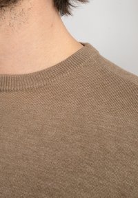Bruin gebreid sweater met een ronde hals. De textuur is zacht, met een gladde oppervlakte en een subtiele glans. Close-up van de stofdetails.