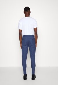 Ljusblå skräddarsydda byxor med två bakfickor och rak framsida, som bärs med en enfärgad vit t-shirt och svarta ank stövlar.