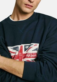 Navy blue sweatshirt with a textured Union Jack print and white accents, featuring a round neckline and ribbed cuffs.