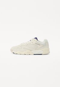 Lacoste sportcipő off-white színben, texturált bőr felsőrésszel. Perforációkkal, sötétkék nyelvvel és vastag fehér gumitalppal rendelkezik.