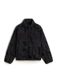 Schwarze Fleecejacke mit strukturierter Oberfläche, ausgestattet mit einem einfarbigen schwarzen horizontalen Einsatz und zwei seitlichen Reißverschlusstaschen.