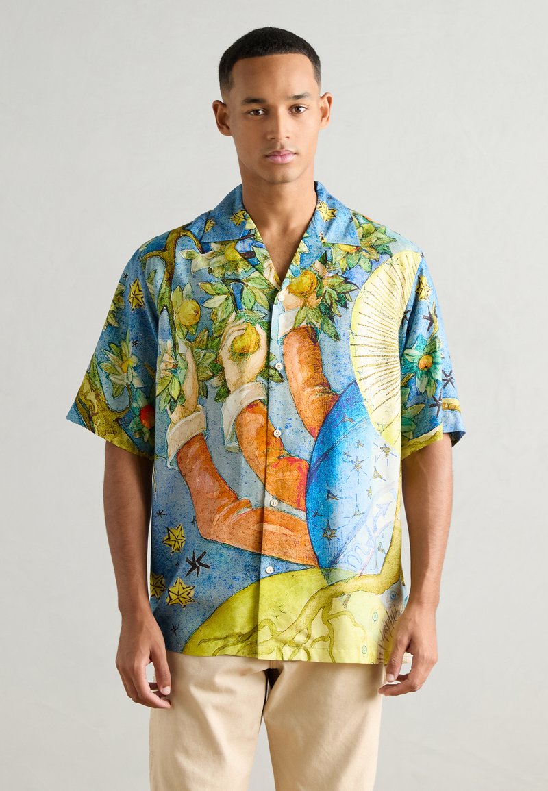 Camisa de botones de manga corta con un estampado vibrante estilo acuarela en azul, verde y amarillo, con ilustraciones florales y dibujadas a mano.