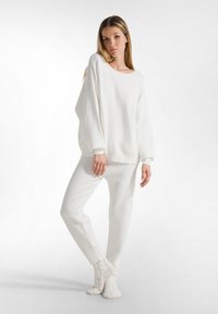 Witte fleece loungewear set met een oversized top met lange mouwen en gefronteerde zoom, gecombineerd met tapered broek en gebreide enkelkousen.