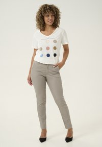 Witte V-hals t-shirt met grafiek van oceankleurendiagram; beige aansluitende broek; zwarte hakken. Soepele stof; lichtgewicht ontwerp.