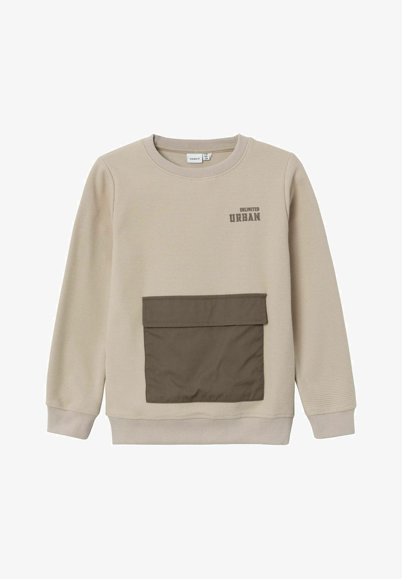 Sweat-shirt beige texturé à col rond, avec une poche avant marron et le texte "UNLIMITED URBAN" en gris foncé. Tissu doux.