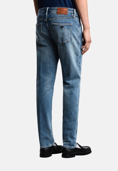 Jeans in denim azzurro chiaro con un design a gamba dritta, caratterizzati da una patch in pelle con il logo sulla vita e due tasche posteriori con dettagli di cucitura.