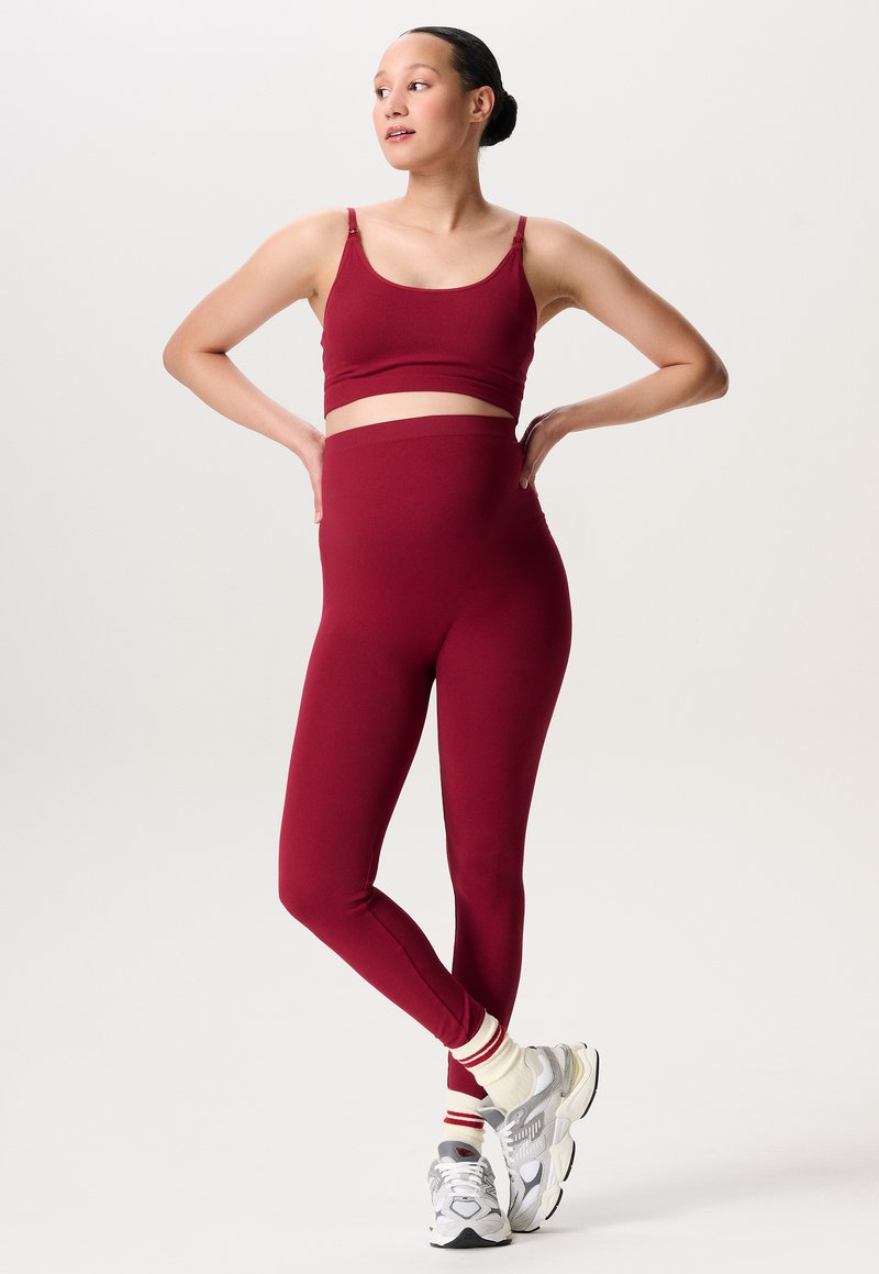 Scharlaken sportbeha en legging set, glad materiaal, nauwsluitend ontwerp, hoge tailleband, gecombineerd met chunky witte sneakers en gestreepte sokken.