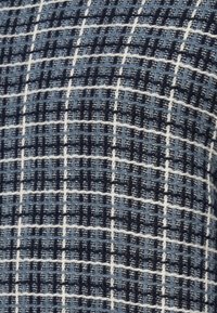 Υφασμάτινη υφή με καρό σχέδιο, που διαθέτει διάφορες αποχρώσεις του μπλε και λευκές λεπτομέρειες. Το υλικό έχει μια μαλακή, υφαντή εμφάνιση.