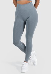 Hoge taille, strakke legging in een lichtgrijze stof, met een soepele textuur en naadloos ontwerp, gecombineerd met witte sportschoenen.