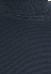 Maglione a coste blu navy con una vestibilità aderente e una texture liscia, caratterizzato da un colletto alto e piegato.