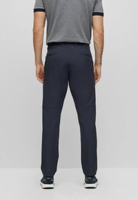 Marina cargo-byxor med en jämn, slitstark tyg, två bakfickor och en tapered passform, tillsammans med svarta och vita sneakers.
