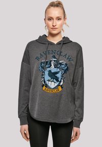 Grå hettegenser med Ravenclaw-emblemet i blått og gult. Løs passform med snøring i hetten, lange ermer og rund nederkant.