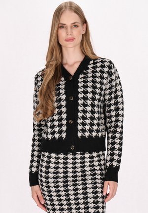 Cardigan cu tipar houndstooth alb-negru, cu decolteu în V, mansete cu nervuri și cinci butoane frontale. Material moale tricotat, design cropped.