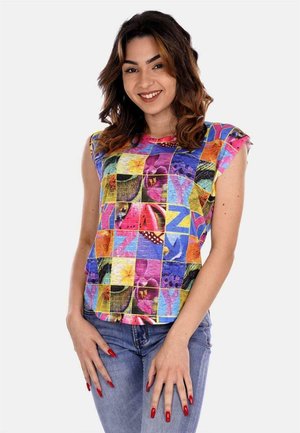 Top corto e colorato a maniche corte con un motivo patchwork di varie forme e colori, realizzato in tessuto leggero, abbinato a jeans blu.