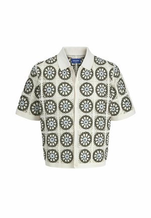 Cardigan in maglia a maniche corte con una base crema e motivi floreali geometrici in verde e azzurro chiaro, rifinito con un colletto.