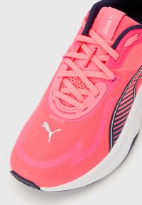 Φωτεινό ροζ παπούτσι για τρέξιμο Puma με λευκό λογότυπο, επάνω μέρος από δίχτυ, ροζ κορδόνια και μαύρη ριγέ λεπτομέρεια στο πλάι σε λευκή σόλα.