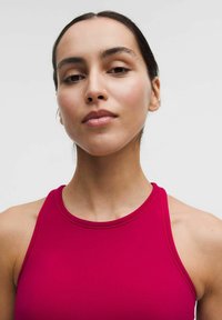 Dopasowany czerwony top sportowy z wysokim dekoltem, cienkimi ramiączkami i gładkim materiałem. Brak widocznych wzorów lub elementów metalowych, czysty design.