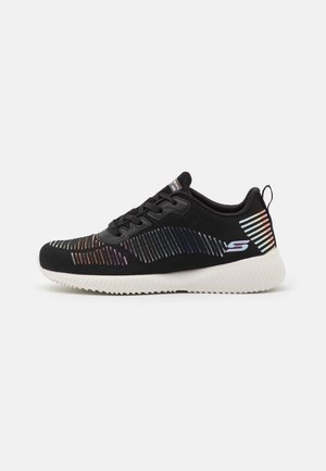 Sort atletiksneaker med hvid sål, flerfarvede refleksstriber, snørelukning foran og trækstrop på hælen, vist i profil.