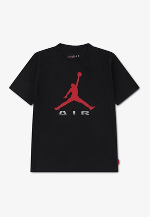 T-shirt noir avec une grande silhouette rouge de basketteur et un texte métallique "AIR" sur le devant au centre. Aucun autre motif visible.
