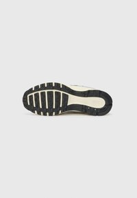 Semelle de sneaker Nike avec un motif en caoutchouc noir texturé, un intersemelle crème et un design uniformément profilé pour une traction et une stabilité optimales.