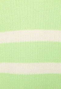 Tessuto lavorato a maglia morbido con righe orizzontali nei colori verde chiaro e bianco sporco, che mostra un primo piano della trama e del motivo dei punti.
