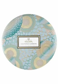 Rund ljusburk med ljusblå bakgrund, dekorerad med intrikata blommönster i guld och grönt. Har en svart etikett med produktinformation.