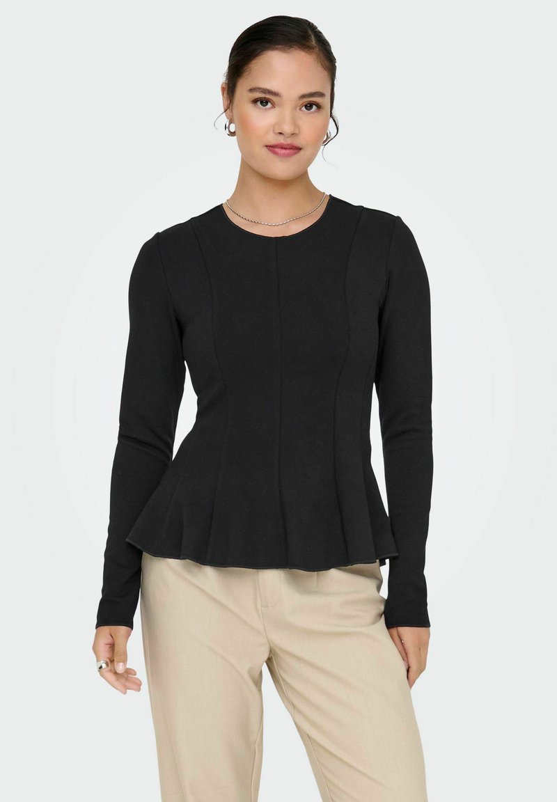 Black long-sleeve top with a fitted bodice and flared peplum hem. Round neckline, textured fabric, paired with light-colored pants.