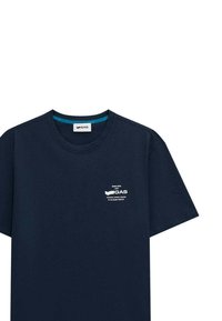 T-shirt in cotone blu navy con maniche corte, scollo rotondo e un logo stampato bianco sul petto. Dotato di un colletto interno teal a contrasto.