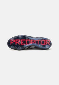 Predator fodboldstøvle ydersål i sort og blå design med rød "PREDATOR" branding, struktureret overflade med faste stålknopper for greb.