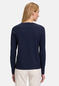Maglione a collo rotondo di colore blu navy a maglia, con maniche lunghe e polsini e fondo a coste. Tessuto morbido con una silhouette aderente.