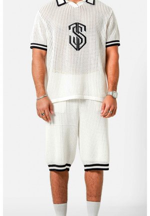 Man draagt een wit mesh T-shirt met korte mouwen en bijpassende korte broek met zwarte bies en een logo op de borst, tegen een witte achtergrond.