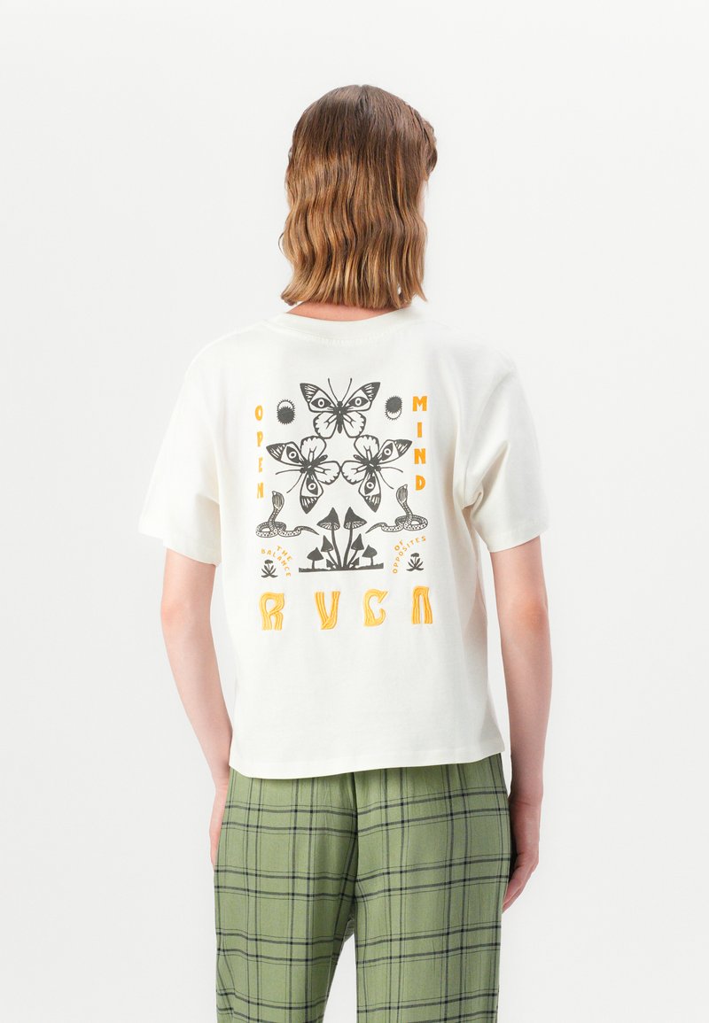 White short-sleeve t-shirt featuring a black and yellow butterfly and botanical graphic on the back, paired with green plaid pants.